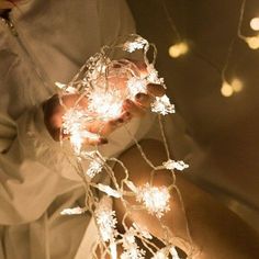 a woman is holding some lights in her hands and wearing white gloves with snowflakes on them