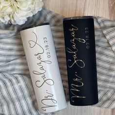 two personalized tumbles sitting on top of a blanket next to a white flower