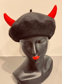 a mannequin head wearing a black hat with red horns on it's ears