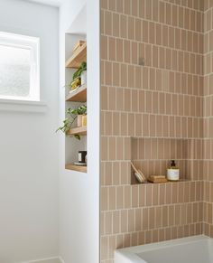 there is a bathtub and shelves in this bathroom with tile on the shower wall