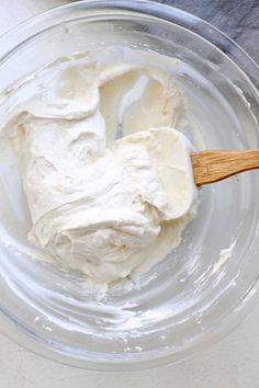 a glass bowl filled with cream and a wooden spoon