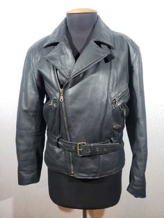 Stylish men's leather biker jacket. Men's black leather jacket with a large metal zipper. The jacket is made of durable black genuine leather. The jacket fastens with a large metal zipper. The jacket has two metal zipper pockets on the right side and two pockets on the left side. The cuffs of the jacket have metal zippers. The jacket has a belt with a metal buckle and a sewn-in elastic on the back. The jacket has a secure inner pocket on the left side. The jacket has a nice polyester lining. The jacket is stylish and reliable, it will emphasize your strong independent style and protect against cold and light rain. MEASUREMENTS: Length                            64 cm |   25 in Pit to pit                          58 cm |  20.5 in Chest circumference     116 cm |   41 in Waist circumference Punk Biker Jacket With Zip Fly For Biker Events, Black Punk Leather Jacket With Zipper, Punk Style Leather Jacket For Motorcycling With Zipper Closure, Punk Leather Biker Jacket With Zipper, Leather Rocker Biker Jacket With Zipper Closure, Leather Biker Jacket With Ykk Zipper, Punk Leather Biker Jacket With Zip Fly, Punk Leather Jacket With Zip Fly, Leather Motorcycle Jacket With Ykk Zipper