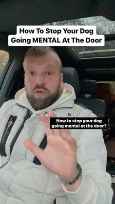 a man sitting in the back seat of a car with his hand up to say how to stop your dog going mental at the door