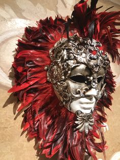 This masquerade mask for man and woman belongs to our collection of feathers' masks. These masks have a crown of red and black feathers. It is perfect for decoration or any masquerade party, Halloween costume, pro or event in Venice or elsewhere during Carnival. This mask can be gently bent to form to your face and ties in the back with two soft matching ribbons. Since the mask is handmade, your mask could be lightly different from the one in the picture. This mask is made on paper mache,decorat Masquerade Party Decorations Red, Artistic Red Masks And Prosthetics For Costume Party, Artistic Red Masks For Costume Party, Artistic Red Mask For Costume Party, Red Fantasy Masquerade Mask For Costume, Artistic Red Masks And Prosthetics For Mardi Gras, Red Fantasy Masks And Prosthetics For Carnival, Artistic Red Masks And Prosthetics For Costume, Red Fantasy Mask For Carnival