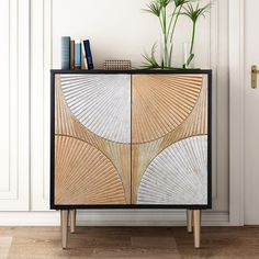 a wooden cabinet with an abstract design on the front and sides, next to a potted plant