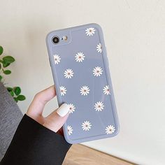 a person holding up a phone case with daisies on it