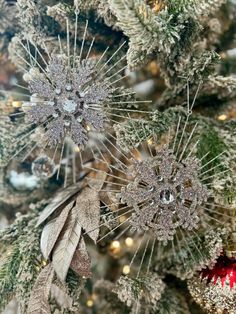 two snowflakes are hanging on the tree in front of other ornaments and decorations