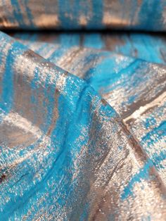 the fabric is shiny and blue with silver spots on it's edges, as well as metallic foil