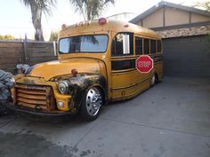 an old yellow school bus is parked in front of a garage with a stop sign on it