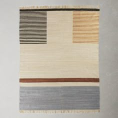 a multicolored rug with stripes and fringes on the bottom is hanging up against a white wall