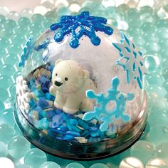 there is a snow globe with a polar bear in it on top of blue glass balls