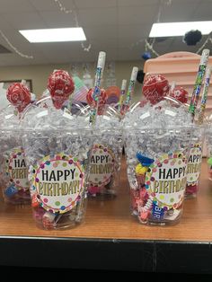 plastic cups filled with candies and lollipops on a table