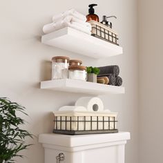 two white shelves with towels, soaps and other bathroom items on them next to a potted plant