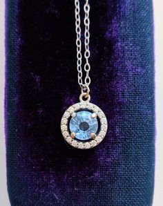 A gorgeous blue sapphire sparkles in the light, accented by a circle of diamonds. Set in 14k white gold, this is the prettiest sapphire necklace you may ever see! Handcrafted in 14k white gold Features a sapphire surrounded by a diamond halo Sapphire measures approx. 5.5mm in diameter Pendant measures approx. 10mm in diameter Full necklace hangs at 18" with a 14k lobster clasp Sapphire Jewelry With Brilliant Cut Round Stone, Sapphire Pendant With Halo Setting, Blue Topaz Round Pendant For Formal Occasions, Dazzling Sapphire Jewelry With Halo Setting, Blue Topaz Jewelry With Halo Setting For Gift, Sapphire Jewelry With Halo Setting, Blue Topaz Jewelry With Halo Setting As A Gift, Formal Blue Topaz Round Pendant Jewelry, Sapphire Necklaces With Halo Setting