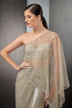 Mist saree gown with all-over sequins embroidery.
Component: 1
Pattern: Embroidered
Type Of Work: Sequin
Neckline: One Shoulder
Sleeve Type: Sleeveless
Fabric: Tulle
Color: Beige
Other Details: 
Strappy back blouse
Sheer panels
Closure: Back zipper
Occasion: Cocktail - Aza Fashions Glamorous Pre-draped Saree With Resham Embroidery For Reception, Organza Pre-draped Saree For Diwali Evening, Glamorous Georgette Dress With Zari Work, Anarkali Style Pre-draped Saree With Sequins For Wedding, Glamorous Organza Pre-draped Saree With Zari Work, Hand Embellished Organza Pre-draped Saree, Semi-stitched Evening Dress With Sheer Dupatta, Glamorous Hand Embellished Diwali Dresses, Glamorous Gown With Sequins In Saree Style