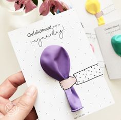 a hand holding a card with a purple flower on it