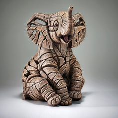 an elephant figurine sitting on the ground with its trunk up and it's eyes open