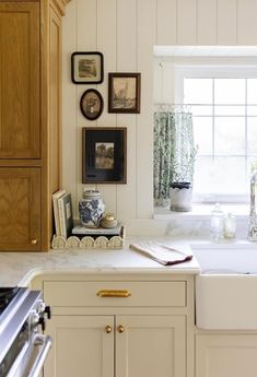 a kitchen with white cabinets and pictures on the wall above the sink, along with an oven