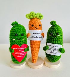 three small crocheted carrots holding signs