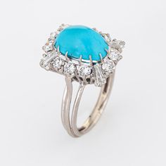 Stylish vintage turquoise & diamond cocktail ring (circa 1950s to 1960s) crafted in 18 karat white gold.   Cabochon turquoise measures 11mm x 8mm (estimated at 5 carats), accented with an estimated 1 carat of mixed cut diamonds (round brilliant and baguette cut). The diamonds are estimated at H-I colour and VS2-SI2 clarity). The turquoise is in very good condition and free of cracks or crisps.    The turquoise is securely set into a multi-pronged mount, surrounded with shimmering diamonds in a s Formal Turquoise Diamond Ring, Formal Turquoise Diamond Ring With Gemstone, Formal Fine Jewelry Turquoise Diamond Ring, Elegant Turquoise Cabochon Diamond Ring, Formal Oval Turquoise Ring With Diamond, Oval Diamond Turquoise Ring For Formal Occasions, Cocktail Jewellery, Cocktail Jewelry, Diamond Cocktail Ring