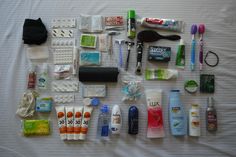 the contents of a travel bag laid out on a bed with toothbrushes, shampoos, and other items