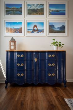 a blue dresser with pictures on the wall above it