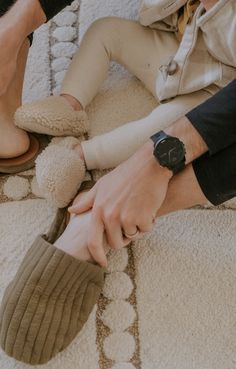 two people sitting on the floor with their feet up and one person wearing slippers