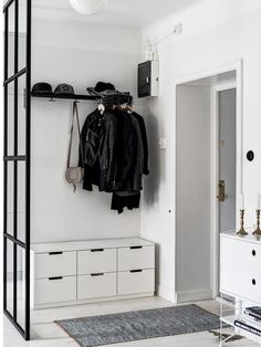 a white room with black and white clothes hanging on the wall next to an open door