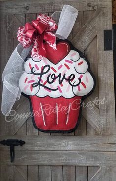 a red and white cupcake door hanger with the word love written on it