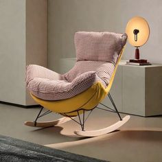 a yellow rocking chair sitting next to a lamp