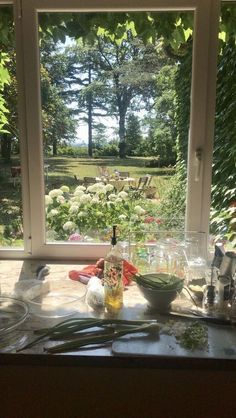 a kitchen counter with bowls and utensils on it, in front of an open window