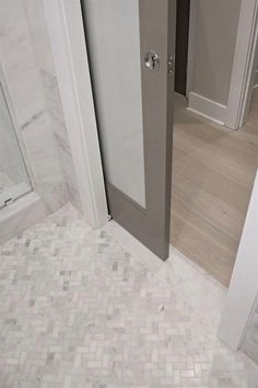 an open door leading to a bathroom with white tile flooring and gray doors on both sides