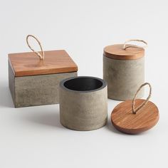 three cement containers with wooden lids and rope on the top one is empty, the other has a lid