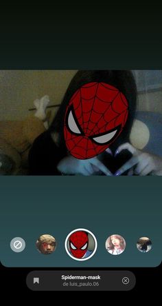 the spiderman mask is on top of someone's head and they are looking at their cell phone