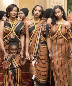 a group of women standing next to each other wearing matching outfits and holding hands together