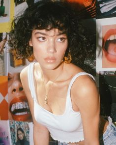 a woman with curly hair wearing a white tank top