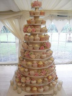 there is a very tall cake with cupcakes on it