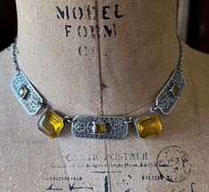 Featuring a unique ornate antique 1920s  Art Deco ornate rhodium plated filigree choker necklace adorned with luminous bezel set faceted Citrine Paste Stones.  Necklace is in excellent antique condition with a functional C spring clasp, minimal wear to plating with all components intact and accounted for.  Necklace measures approximately 15 inches around at 14.4 grams respectively and is beautifully designed and handcrafted.  A collectible wearable Heirloom necklace! Please feel free to contact Heirloom Necklace, Stones Necklace, 1920s Art, 1920s Art Deco, Art Deco Era, Choker Necklaces, Antique Art Deco, Antique Art, Rhodium Plated