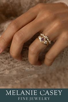 a woman's hand wearing a gold ring with three stones on it and the words melanie casey fine jewelry