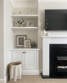 a living room with a fireplace, tv and shelves