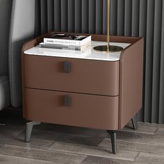 a nightstand with two drawers and a lamp on it next to a gray leather chair