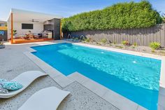 an empty swimming pool in the middle of a backyard with chaise lounges around it