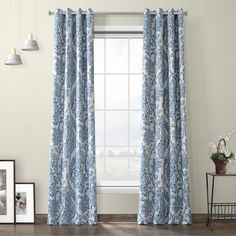 the curtains in this room are blue with white flowers on them, and one window is closed