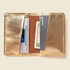 A shinny metallic leather makes for a perfect and easy wallet to find anywhere! A super sleek bifold designed to keep your cards and cash organized. This handcrafted product was created in California using leather rescued from the past. CASUPO searches for beautiful pieces all over the world, finding treasures and giving rediscovered leathers new life, new purpose, a new future of style. This sustainable collection of newly found leather lessens the amount of waste in the world to create a truly eco-friendly leather line. This leather is tanned by hand. You'll notice color and grain variation or unique markings on each one, ensuring every Casupo product is an original. This wallet can be personalized with your initials embossed on the inside bottom right corner. NOTE: Monogrammed orders ar Gold Wallets With Gold-tone Hardware For Everyday Use, Elegant Wallet With Gold-tone Hardware, Luxury Gold Wallets With Gold-tone Hardware, Leather Clutch Wallet With Gold-tone Hardware, Leather Wallets With Gold-tone Hardware, Cash Organizer, Simple Wallet, Clip Wallet, Small Wallet