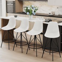 four white bar stools sit in front of an island