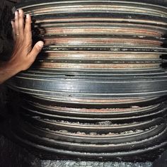 a stack of metal plates stacked on top of each other with one hand reaching for it