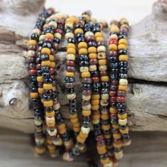 multicolored beads are stacked on top of each other near a piece of driftwood