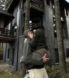 two people hugging each other in front of a house