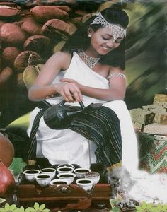 a woman in white dress sitting on top of a wooden box filled with cups and bowls