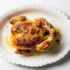 a cooked chicken is sitting on a white plate